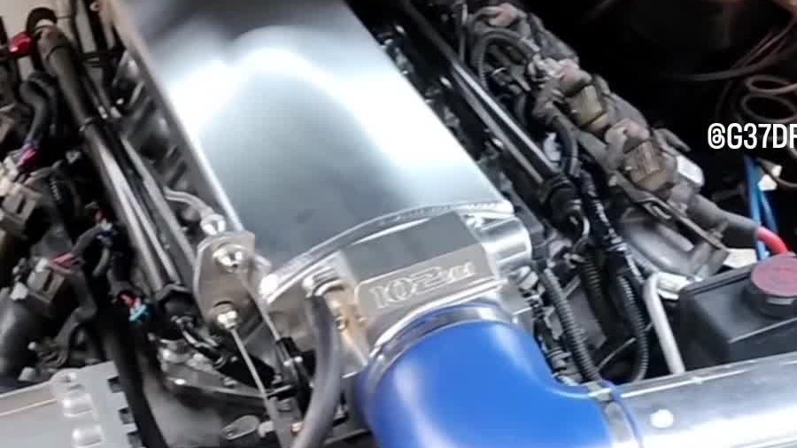Engine bay with a polished cover, blue intake coupler, and a compressor on the crank